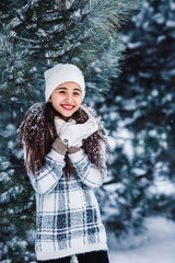 Stylish cheerful girl strewn with snow in the winter forest.