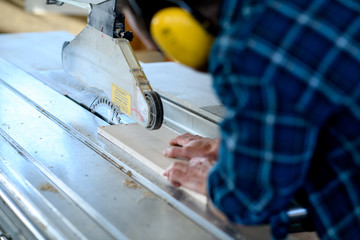 young worker in a carpenter's workshop using saw