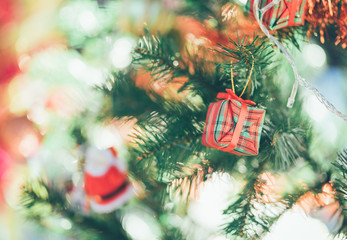 Gift box hanging on a green pine. Decorated Christmas tree on blurred, Sparkling and fairy background