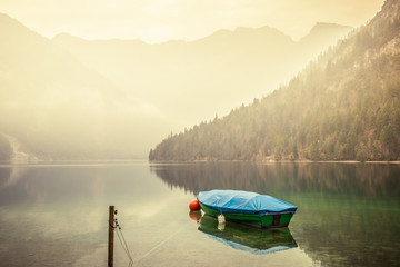 Small boat on lake Plansee in the European Alps, in Austria at early morning sunrise