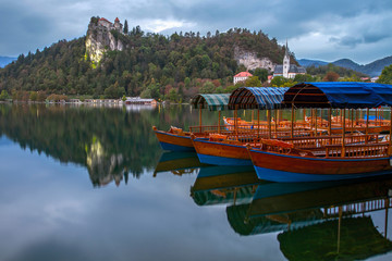 Tourist boats on the on Lake Bled. Beautiful mountain lake Bled and Medieval castle on the rock. Scenery at Bled lake in Slovenia. Mountains in background. Slovenia, Europe. European travel.