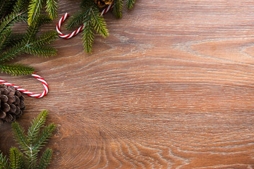 Christmas composition background on wood table with pine branches with cones and candy canes. Top view with copy space, flat lay.
