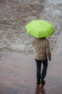 Mulhouse - France - 28 October 2018 - portrait of man walking with green umbrella on cobbles place
