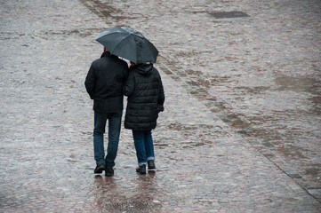 Mulhouse - France - 28 October 2018 - portrait of couple  walking with blue umbrella on cobbles place