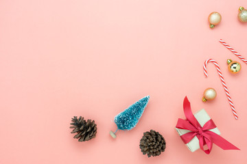 Table top view of Merry Christmas decorations & Happy new year ornaments concept.Flat lay essential difference objects gift box & fir tree with pine cones and decor on modern pink paper background.