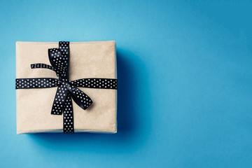 Wrapped gift box with ribbon bow on a blue background with copy space