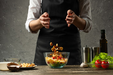 Freezing food prepares a vegetarian salad with seafood by the chef in the home kitchen. A concrete wall background with a text area for restaurant menu design.