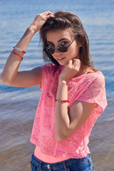 The girl in pink clothes posing against the background of water