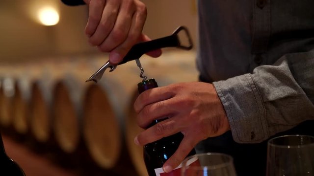 Man opening wine bottle in cellar for tasting