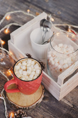 hot cocoa with marshmallows on wooden table with christmas lights. Cozy winter home concept