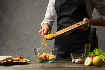 Freezing food prepares a vegetarian salad with seafood by the chef in the home kitchen. A concrete wall background with a text area for restaurant menu design.