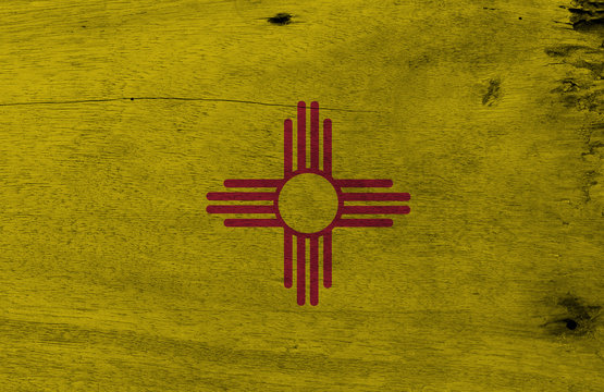 Flag of New Mexico on wooden plate background. Grunge New Mexico flag texture, The states of America. The red and yellow of old Spain. The ancient Zia Sun symbol in red.