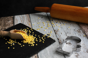 Glove cookie cutter with yellow sugar stars and rolling pin on wooden board, high angle view, copy space