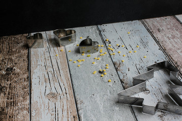 Christmas tree cookie cutter and heart cookie cutters with yellow sugar stars on wooden board, high angle view, copy space