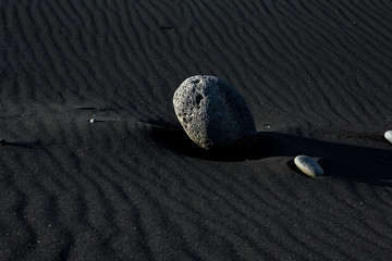 Grey lava stones in iceland. Vulcanic sand beach. Volcanic rock on black sand.
