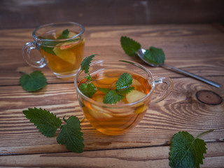 Tea with apples in glass mugs, a teaspoon on a warm wooden background