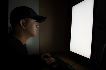 Side view of man Hacker sit at the computer monitor. in the dark room.
