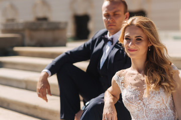 Fashion photo of wedding couple. Groom wears blue suit and tie bow. Bride wears white wedding dress