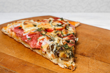 Italian rustic pizza, one piece on a wooden tray, white wooden table
