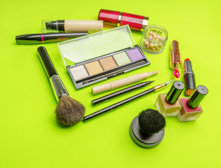 The composition of accessories, makeup cosmetics on a bright green background. Top view.   