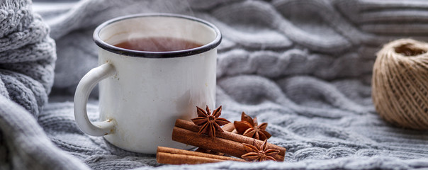 The conception of cozy and warmth. A Cup of hot fragrant tea, soft knitted plaid and spices on the...
