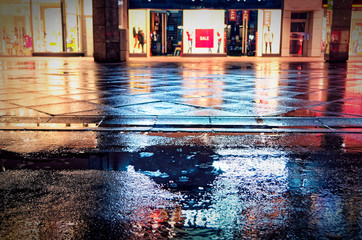 German inner city with closed shops and sale with pedestrian zone in rain and night with red lights - obrazy, fototapety, plakaty