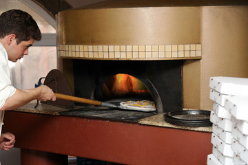 Piekarz wkłada pizzę do pieca.