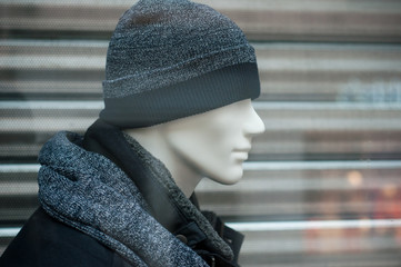 closeup of wool hat and blue winter coat on mannequin in fashion store showroom for men
