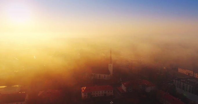 Beautiful Aerial Shot of Misty Sunrise in small town. Colorful clouds, fog above the city.