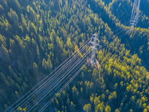 Aerial view of power line pylon in mountaineous area in Switzerland through valley in Canton of Valais