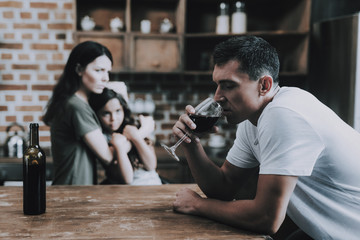 Mother and Child Look at Drunk Father in Kitchen