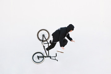 The Bmx rider falls into the dark background with a white background. Bmx and a cyclist are flying on a white background. Bmx rider is isolated on a white background.