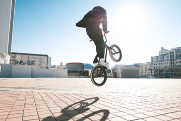 Bmx rider makes a trick in the jump on the street in the background of the city landscape and the...