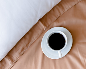 cup of coffee on the bed. bed linen. light from the window