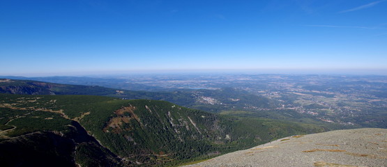 Widok ze Śnieżki w stronę Karpacza, ziemia stykająca się z niebem na horyzoncie © Konrad_elx