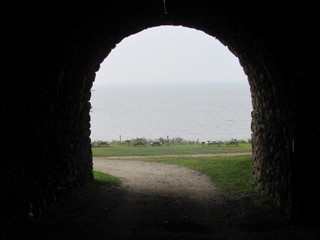 View of the ocean through a stone archway on a foggy day 