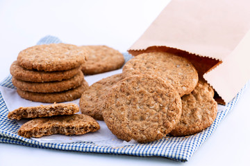 Homemade shortbread cookies made of oatmeal are stacked on cloth and paper bag on white table background. Concept food healthy snack for enjoy in holiday. With copy space for text.