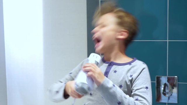 Portrait of happy little white kid dancing and singing cheerfully at bathroom. Real time 4k video footage.