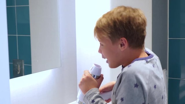 Profile view of happy cute little boy sings song in bathroom using hair dryer as microphone. Portrait of happy creative future little singer. Real time 4k video footage.