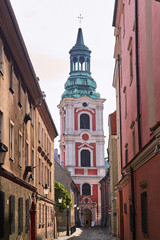 Fototapeta na wymiar Baroque monastery tower and a cobbled street in Poznan.