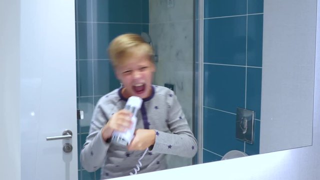 Portrait of happy little white kid dancing and singing cheerfully at bathroom. Real time 4k video footage.