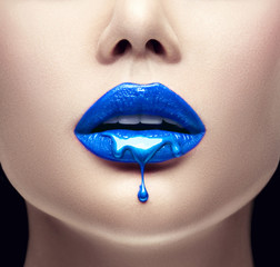 Blauer Lippenstift tropft. Lipgloss tropft von sexy Lippen, blaue Flüssigkeitstropfen auf den Mund des schönen Modellmädchens, kreatives abstraktes Make-up