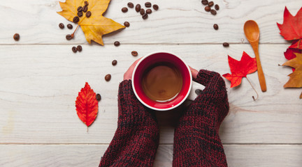 Manos cogiendo una taza de cafe caliente en otoño