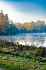 the lake is surrounded by autumn trees reflected in the mirror surface of the lake, quiet morning