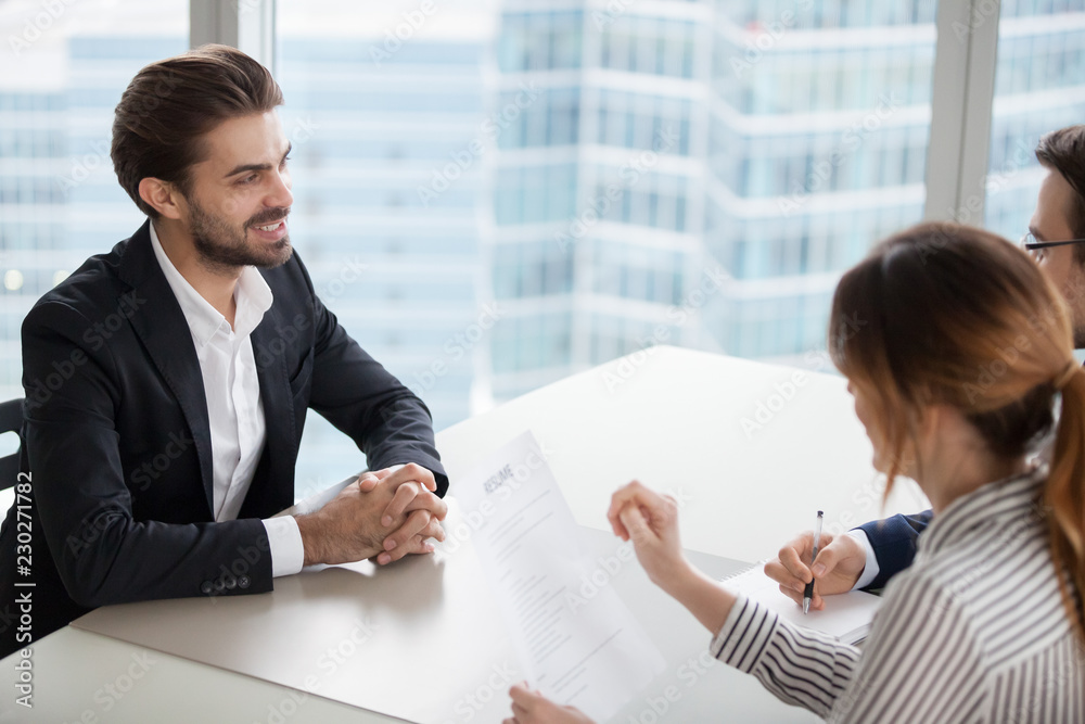 Poster Young man at job interview answering questions of employer. Two HR managers talking with successful candidate for vacancy. Hiring, staff recruiting process.