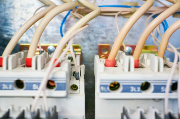 Two electric three-phase switches connected by wires on a metal background.
