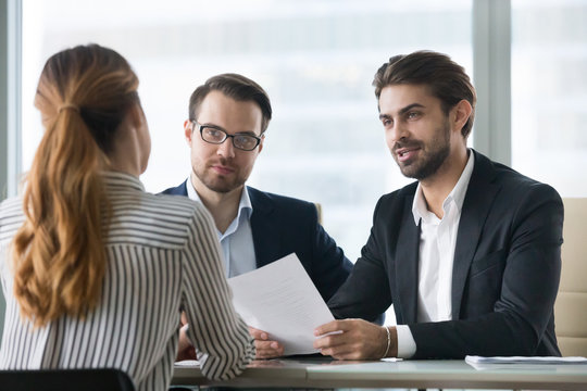 Two Male Hr Managers At Interview With Female Applicant. Man With Resume In Hands Asks Questions To Candidate. Hiring, Staff Recruiting Process.