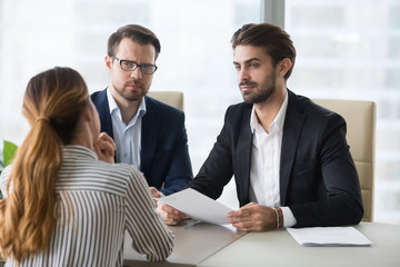 Two hr managers looking with disbelief at female applicant. Skeptic employer. Candidate lied in resume, bad cv. No hiring, staff recruiting process, bad first impression.