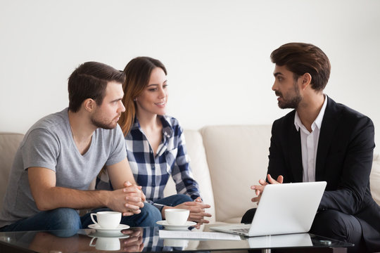 Young couple, family at meeting with realtor, interior designer, decorator, landlord. Employee consulting, showing sketches on laptop. Concept of meeting with client, customer.