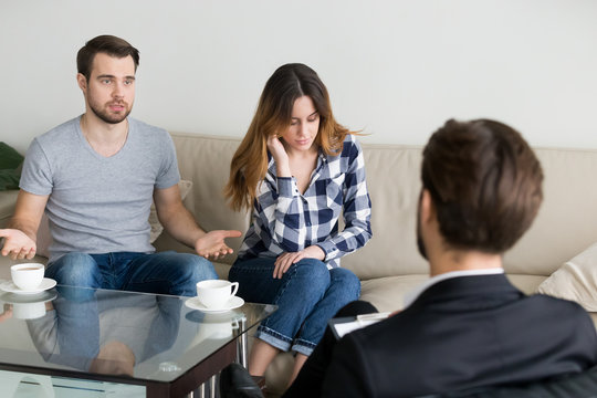 Young couple, family at meeting session with psychologist counselor doctor. Family problems, misunderstanding, distrust, addiction. Husband talking about symptoms and problems. Woman no desire to talk